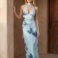Aleena cowl neck halter maxi dress with a deep draped neckline, fitted halter strap, open back with tie-neck closure, sleeveless column silhouette, and floor-length straight hem in a smooth, elegant finish.