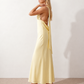 Aleena cowl neck halter maxi dress with a deep draped neckline, fitted halter strap, open back with tie-neck closure, sleeveless column silhouette, and floor-length straight hem in a smooth, elegant finish.