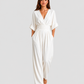 Women's deep V-neck wide-leg jumpsuit with cinched waist, relaxed rolled sleeves, lightweight flowing fabric and side pockets in an elegant silhouette.