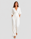 Women's deep V-neck wide-leg jumpsuit with cinched waist, relaxed rolled sleeves, lightweight flowing fabric and side pockets in an elegant silhouette.