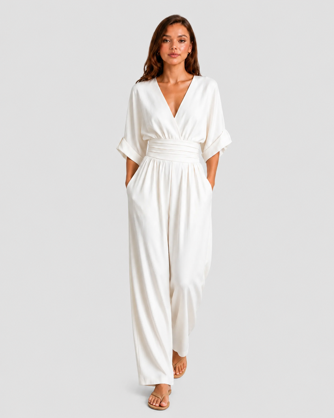 Women's deep V-neck wide-leg jumpsuit with cinched waist, relaxed rolled sleeves, lightweight flowing fabric and side pockets in an elegant silhouette.