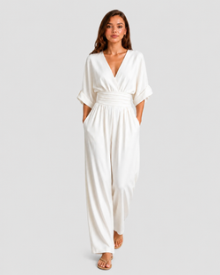Women's deep V-neck wide-leg jumpsuit with cinched waist, relaxed rolled sleeves, lightweight flowing fabric and side pockets in an elegant silhouette.