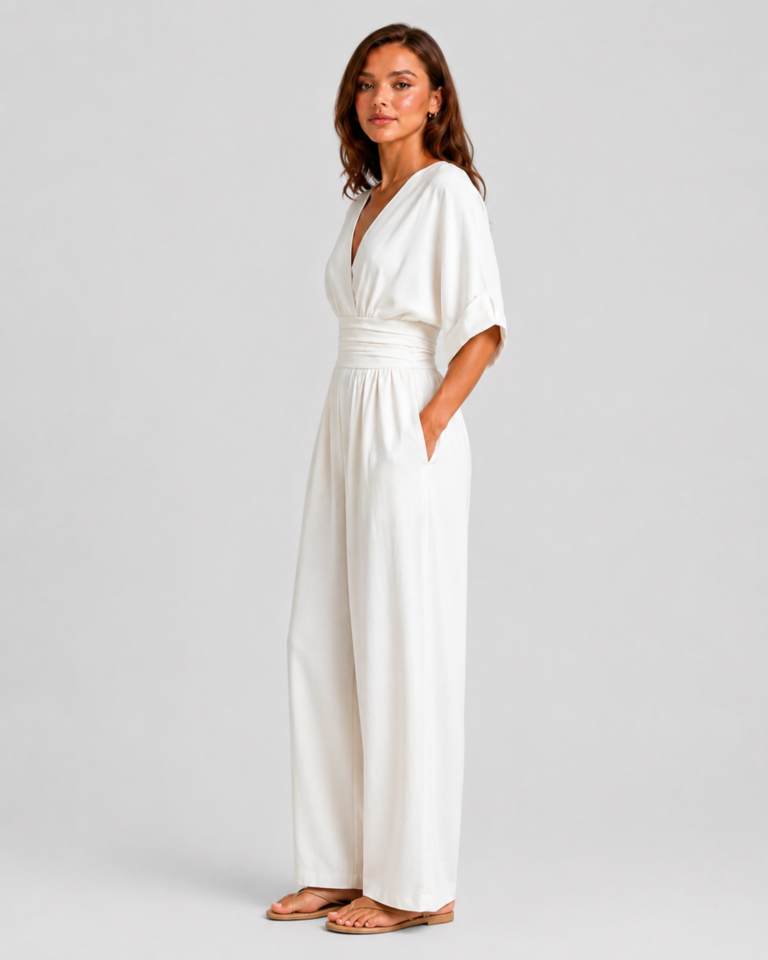 Women's deep V-neck wide-leg jumpsuit with cinched waist, relaxed rolled sleeves, lightweight flowing fabric and side pockets in an elegant silhouette.