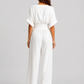 Women's deep V-neck wide-leg jumpsuit with cinched waist, relaxed rolled sleeves, lightweight flowing fabric and side pockets in an elegant silhouette.