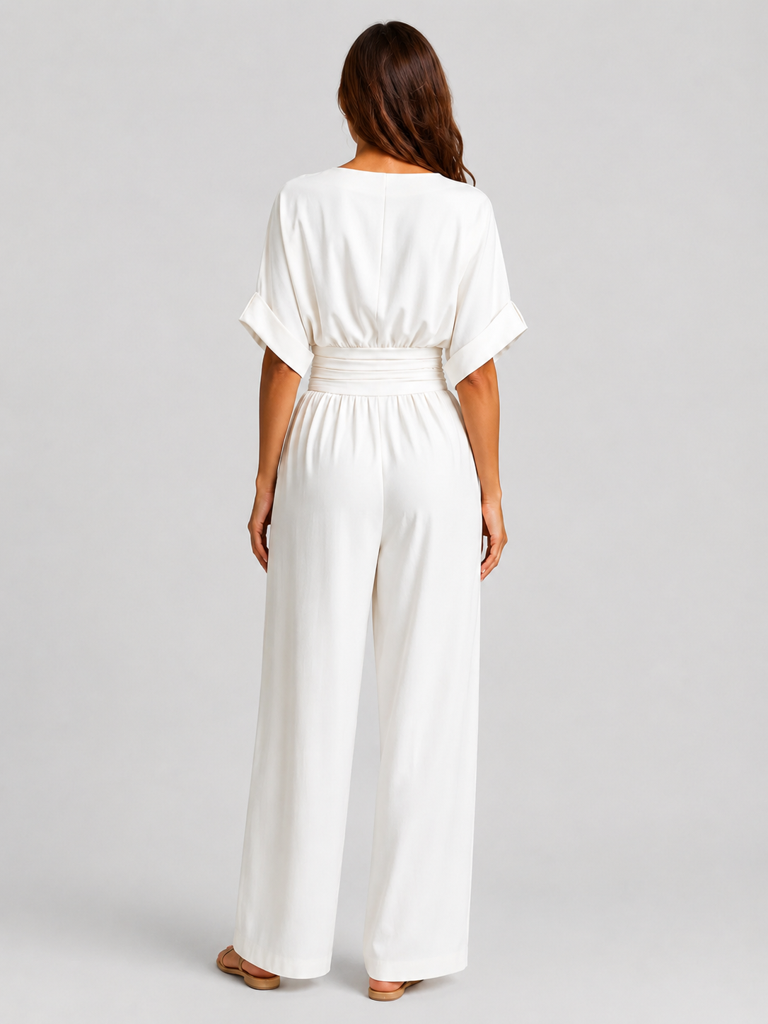 Women's deep V-neck wide-leg jumpsuit with cinched waist, relaxed rolled sleeves, lightweight flowing fabric and side pockets in an elegant silhouette.