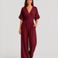 Women's deep V-neck wide-leg jumpsuit with cinched waist, relaxed rolled sleeves, lightweight flowing fabric and side pockets in an elegant silhouette.