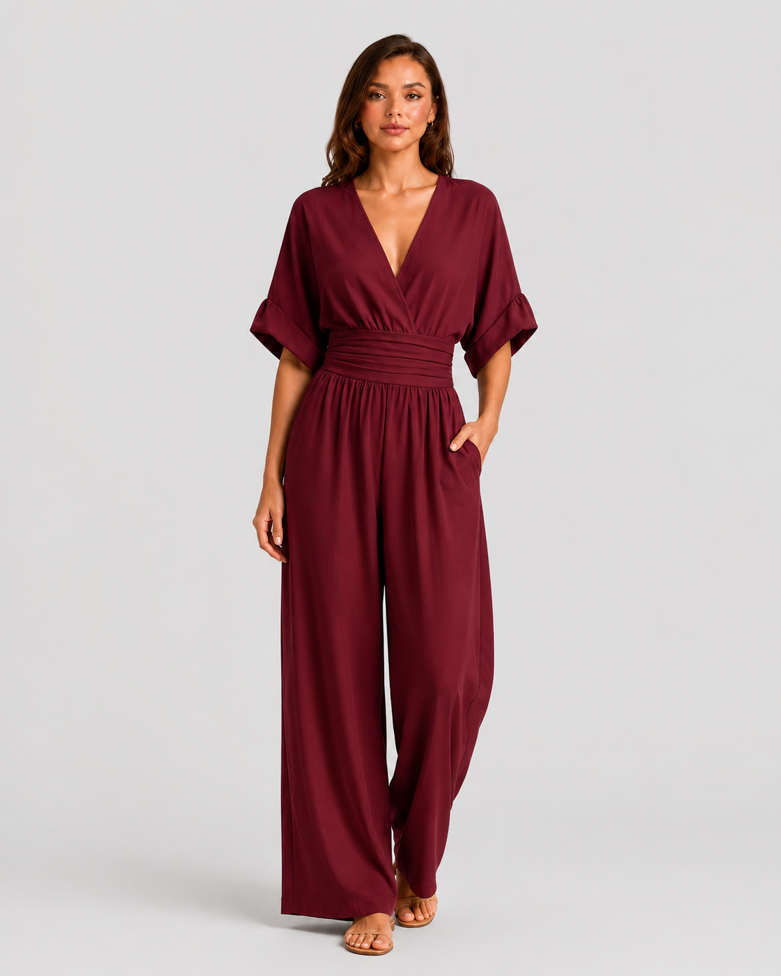Women's deep V-neck wide-leg jumpsuit with cinched waist, relaxed rolled sleeves, lightweight flowing fabric and side pockets in an elegant silhouette.