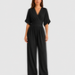 Women's deep V-neck wide-leg jumpsuit with cinched waist, relaxed rolled sleeves, lightweight flowing fabric and side pockets in an elegant silhouette.