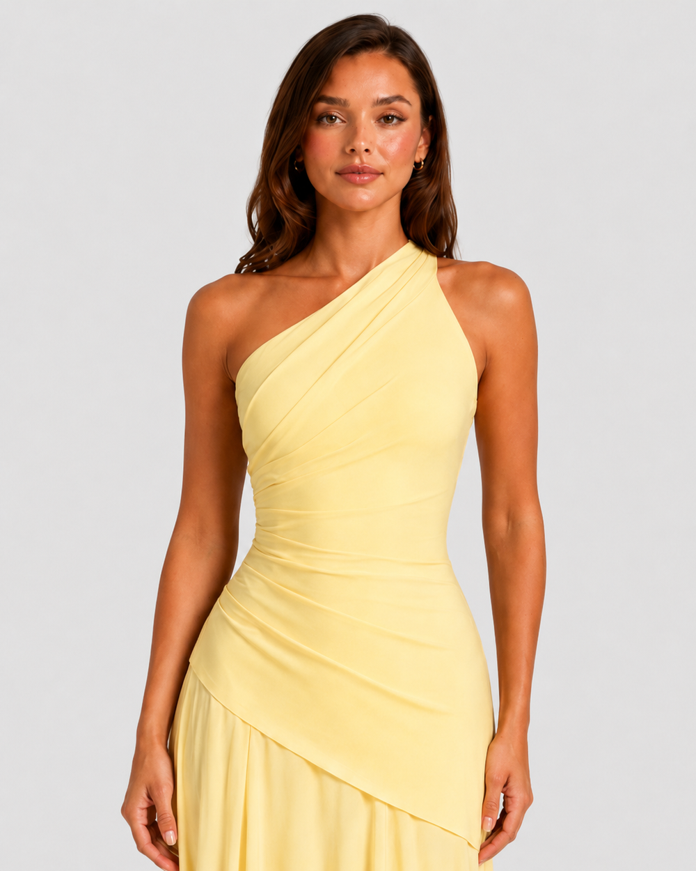 Woman wearing a one-shoulder chiffon maxi dress featuring a pleated neckline, corset bodice with lace-up back, and flowing godet skirt in an elegant formal silhouette.