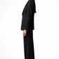 Woman wearing a black suit standing against a white background
