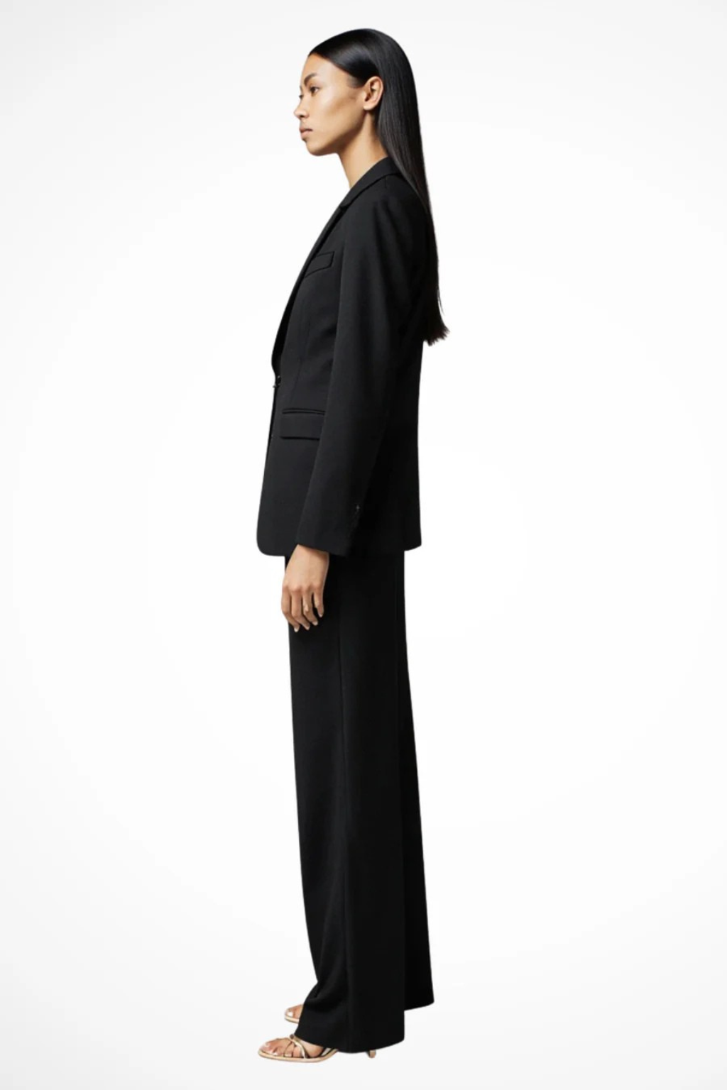Woman wearing a black suit standing against a white background