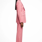 Woman wearing a pink suit standing against a white background