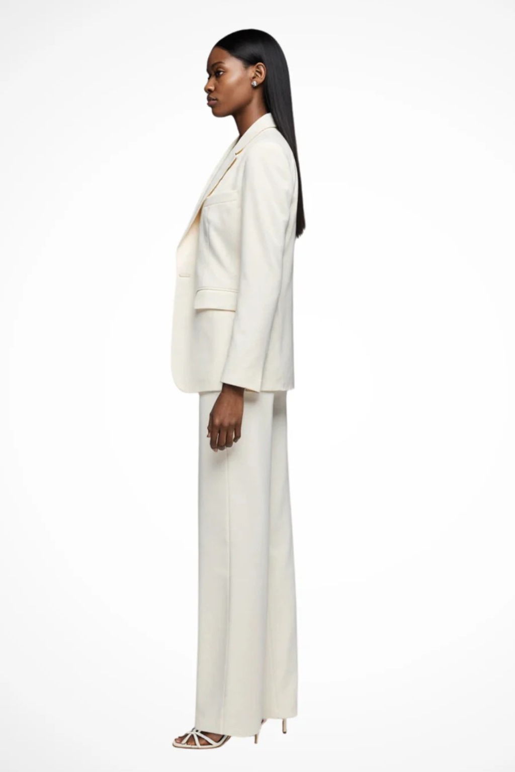 Woman wearing a white suit standing against a white background