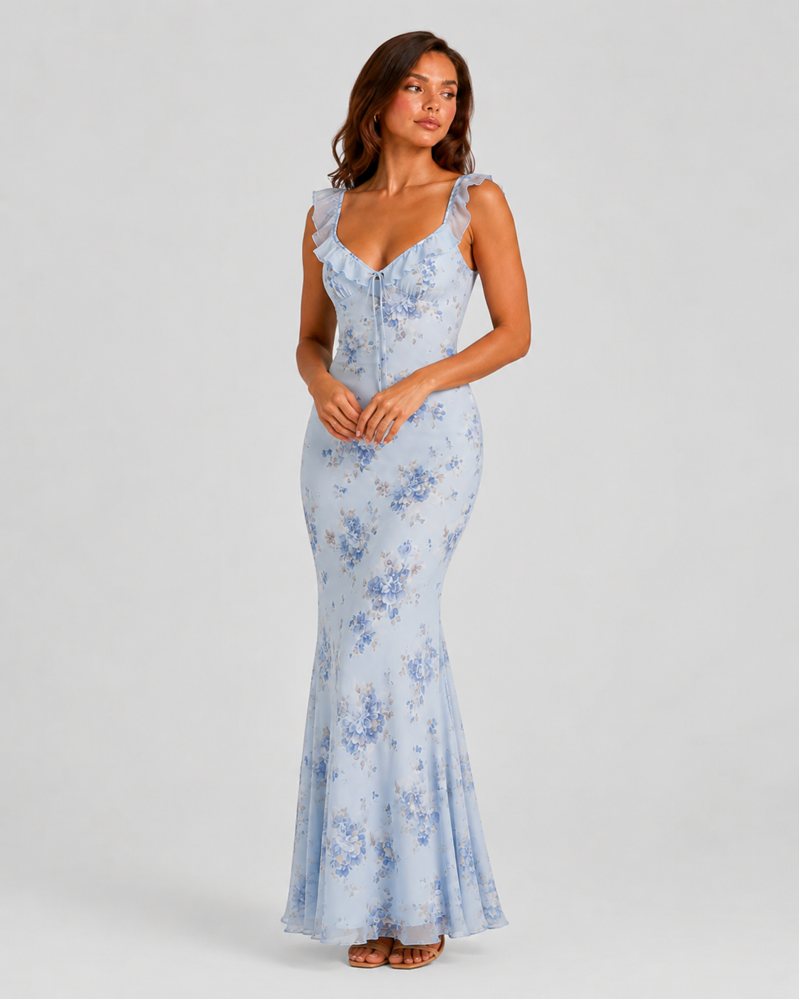 Woman wearing a floral maxi dress with delicate ruffle straps, slim-fit silhouette, flowing lightweight fabric, and romantic summer styling.