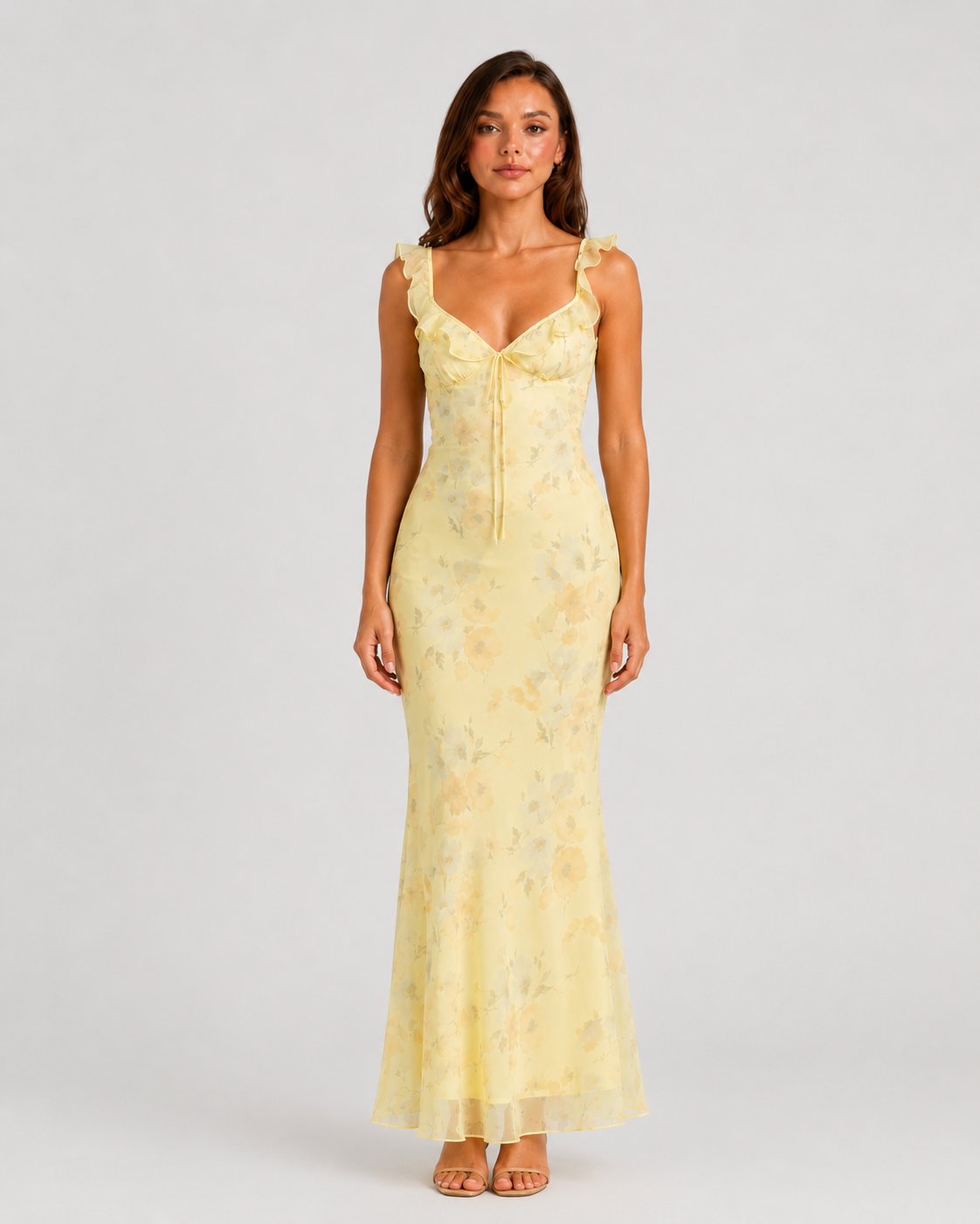 Woman wearing a floral maxi dress with delicate ruffle straps, slim-fit silhouette, flowing lightweight fabric, and romantic summer styling.