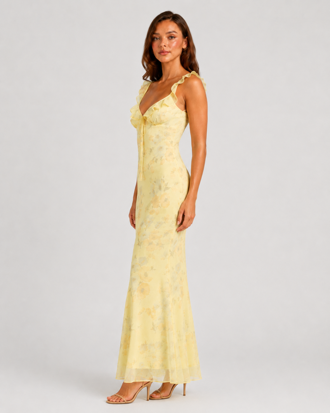 Woman wearing a floral maxi dress with delicate ruffle straps, slim-fit silhouette, flowing lightweight fabric, and romantic summer styling.