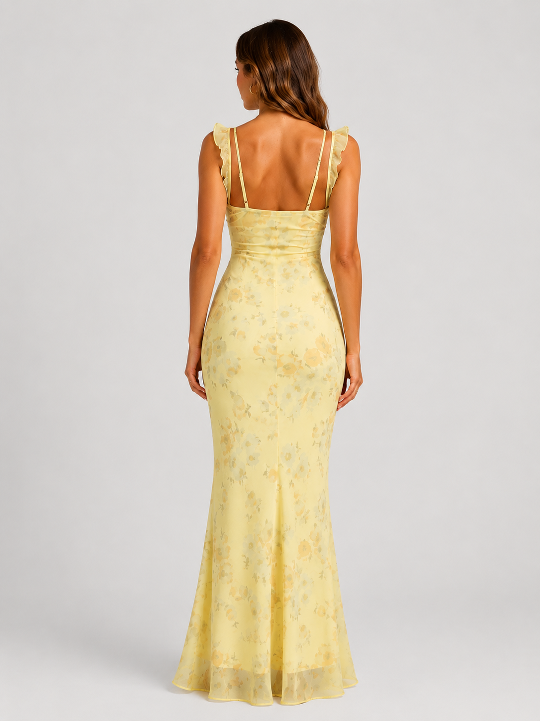 Woman wearing a floral maxi dress with delicate ruffle straps, slim-fit silhouette, flowing lightweight fabric, and romantic summer styling.