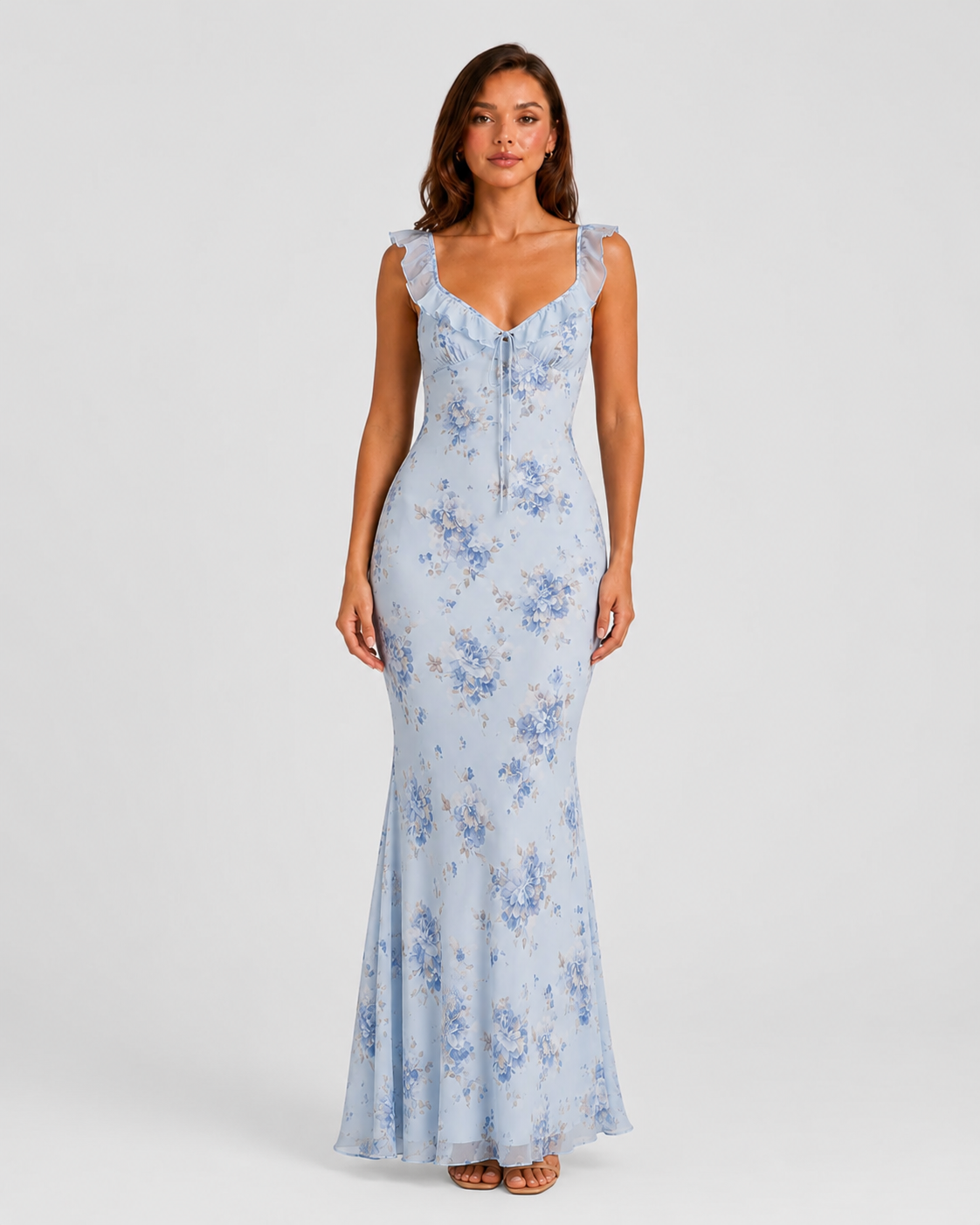 Woman wearing a floral maxi dress with delicate ruffle straps, slim-fit silhouette, flowing lightweight fabric, and romantic summer styling.