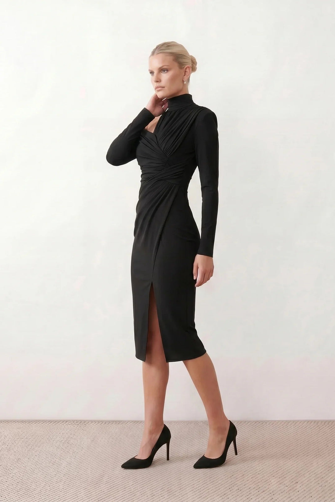Woman wearing the Felisa Asymmetric Neck Open Back Midi Dress featuring an asymmetric mock-neck halter, off-shoulder ruched detailing, long fitted sleeves, an elegant open back, fitted midi silhouette and front slit, styled for weddings, cocktail parties and formal occasions.