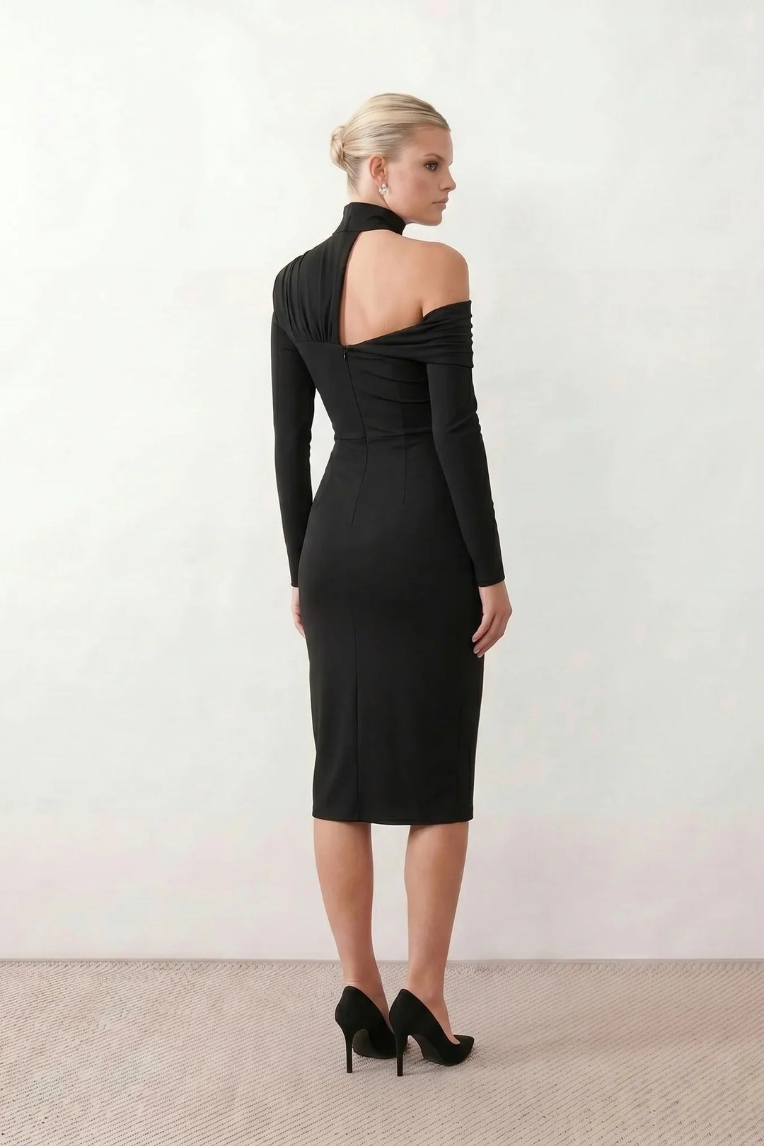 Woman wearing the Felisa Asymmetric Neck Open Back Midi Dress featuring an asymmetric mock-neck halter, off-shoulder ruched detailing, long fitted sleeves, an elegant open back, fitted midi silhouette and front slit, styled for weddings, cocktail parties and formal occasions.