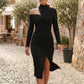 Woman wearing the Asymmetric Neck Open Back Midi Dress featuring an asymmetric mock-neck halter, off-shoulder ruched detailing, long fitted sleeves, an elegant open back, fitted midi silhouette and front slit, styled for weddings, cocktail parties and formal occasions.