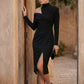 Woman wearing the Asymmetric Neck Open Back Midi Dress featuring an asymmetric mock-neck halter, off-shoulder ruched detailing, long fitted sleeves, an elegant open back, fitted midi silhouette and front slit, styled for weddings, cocktail parties and formal occasions.