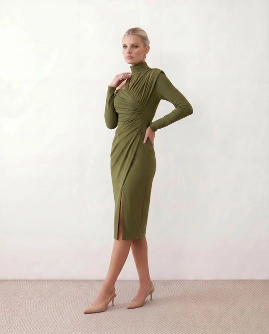 Woman wearing the Felisa Asymmetric Neck Open Back Midi Dress featuring an asymmetric mock-neck halter, off-shoulder ruched detailing, long fitted sleeves, an elegant open back, fitted midi silhouette and front slit, styled for weddings, cocktail parties and formal occasions.