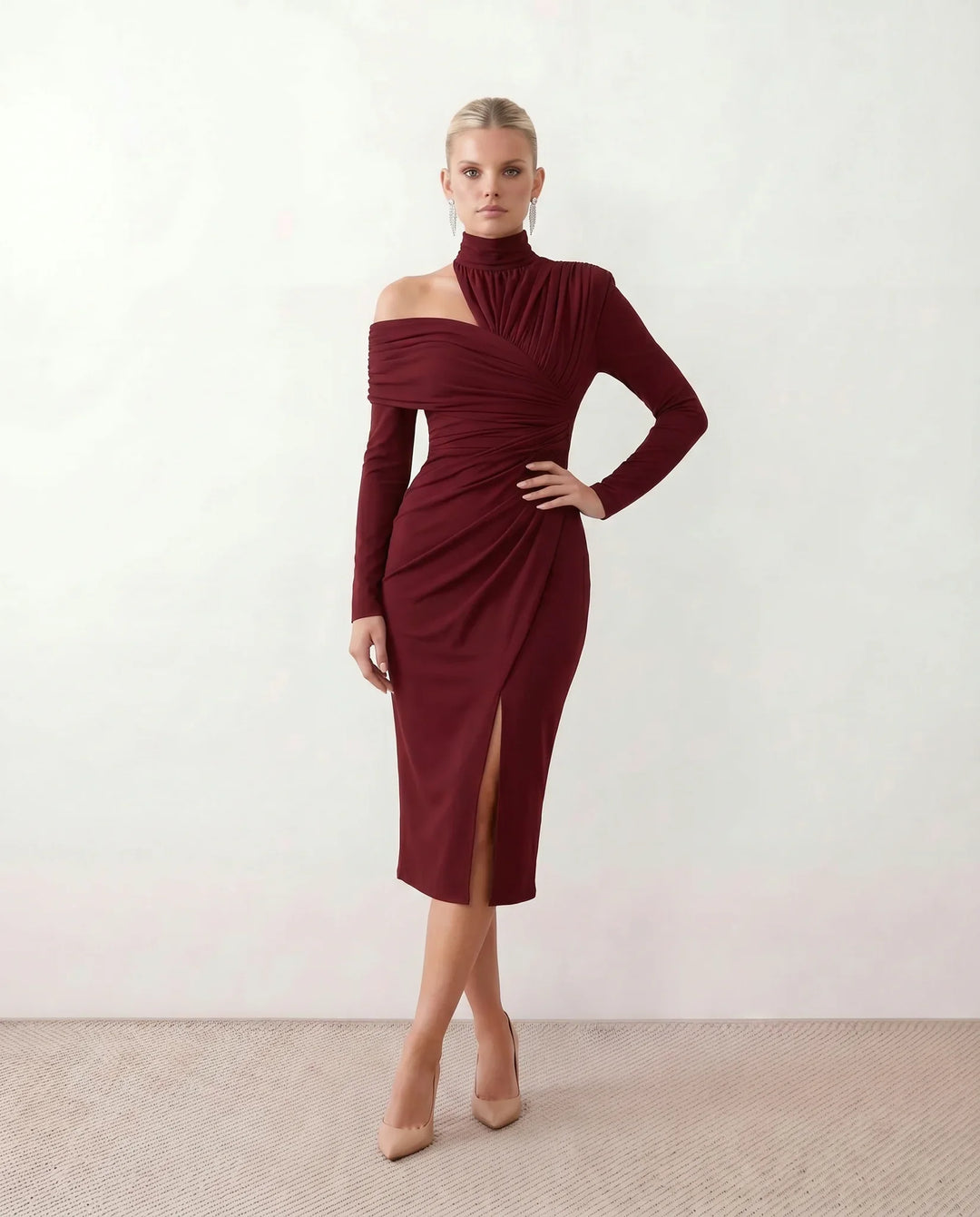 Woman wearing the Felisa Asymmetric Neck Open Back Midi Dress featuring an asymmetric mock-neck halter, off-shoulder ruched detailing, long fitted sleeves, an elegant open back, fitted midi silhouette and front slit, styled for weddings, cocktail parties and formal occasions.