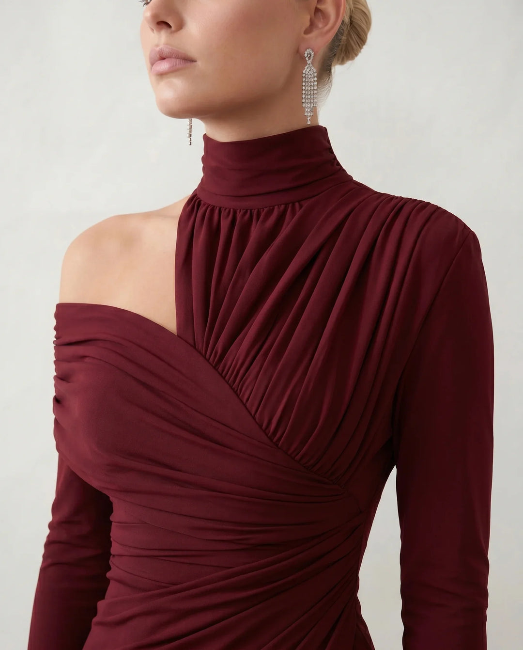 Woman wearing the Felisa Asymmetric Neck Open Back Midi Dress featuring an asymmetric mock-neck halter, off-shoulder ruched detailing, long fitted sleeves, an elegant open back, fitted midi silhouette and front slit, styled for weddings, cocktail parties and formal occasions.