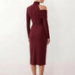 Woman wearing the Asymmetric Neck Open Back Midi Dress featuring an asymmetric mock-neck halter, off-shoulder ruched detailing, long fitted sleeves, an elegant open back, fitted midi silhouette and front slit, styled for weddings, cocktail parties and formal occasions.