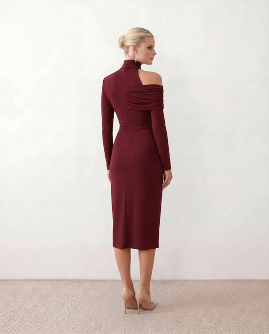 Woman wearing the Felisa Asymmetric Neck Open Back Midi Dress featuring an asymmetric mock-neck halter, off-shoulder ruched detailing, long fitted sleeves, an elegant open back, fitted midi silhouette and front slit, styled for weddings, cocktail parties and formal occasions.