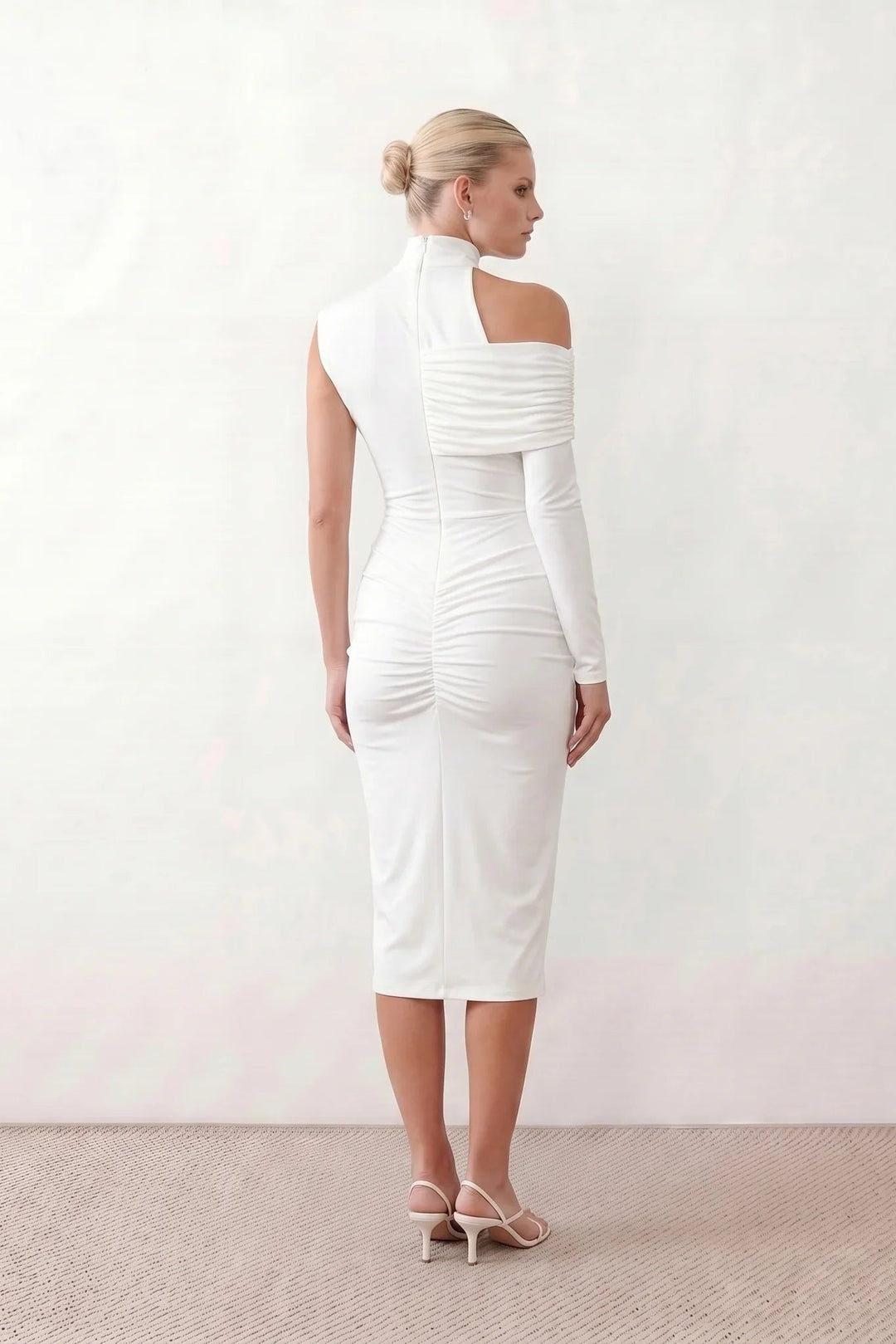 Woman wearing the Felisa Asymmetric Neck Open Back Midi Dress featuring an asymmetric mock-neck halter, off-shoulder ruched detailing, long fitted sleeves, an elegant open back, fitted midi silhouette and front slit, styled for weddings, cocktail parties and formal occasions.
