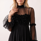 Women's Yasmine Flower Appliqué Mini Dress featuring delicate floral appliqué across the bodice, a sheer mock neckline, ruffled long sleeves, and a flattering skater mini silhouette, ideal for weddings, cocktail parties, race days, and special occasions.