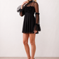 Women's Yasmine Flower Appliqué Mini Dress featuring delicate floral appliqué across the bodice, a sheer mock neckline, ruffled long sleeves, and a flattering skater mini silhouette, ideal for weddings, cocktail parties, race days, and special occasions.