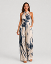 Woman wearing a printed halter neckline wide-leg jumpsuit with a relaxed fit, breathable fabric, side pockets and flowing resort-inspired silhouette.