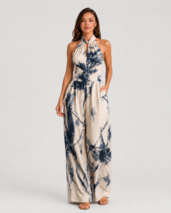 Woman wearing a printed halter neckline wide-leg jumpsuit with a relaxed fit, breathable fabric, side pockets and flowing resort-inspired silhouette.