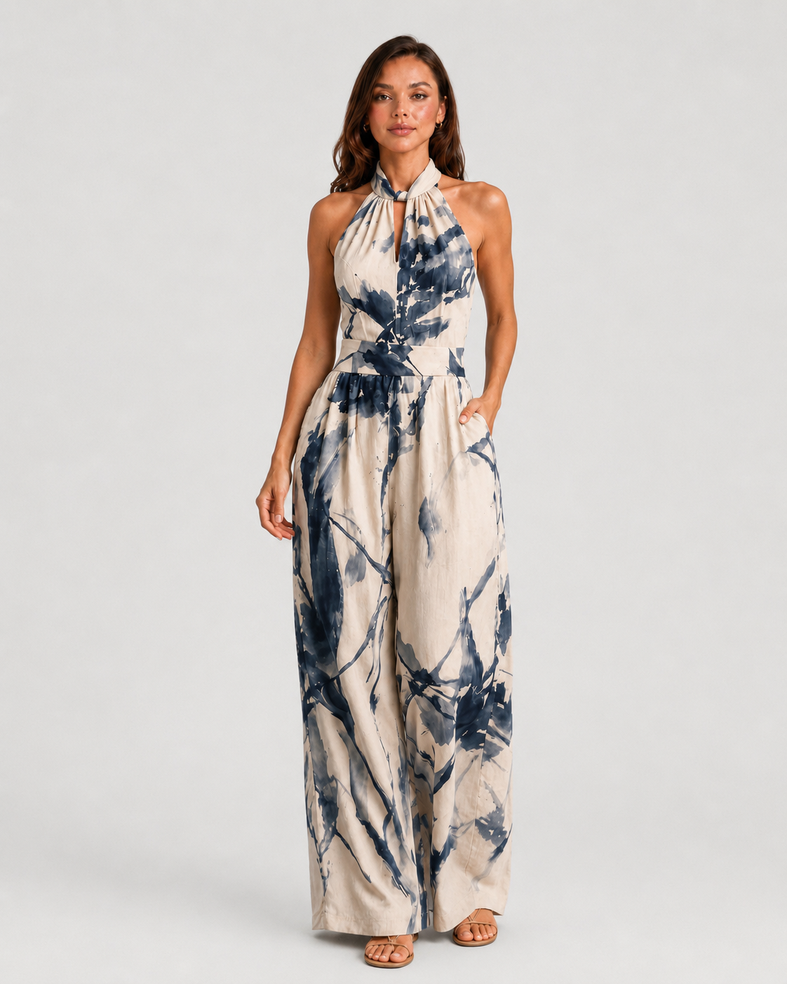 Woman wearing a printed halter neckline wide-leg jumpsuit with a relaxed fit, breathable fabric, side pockets and flowing resort-inspired silhouette.