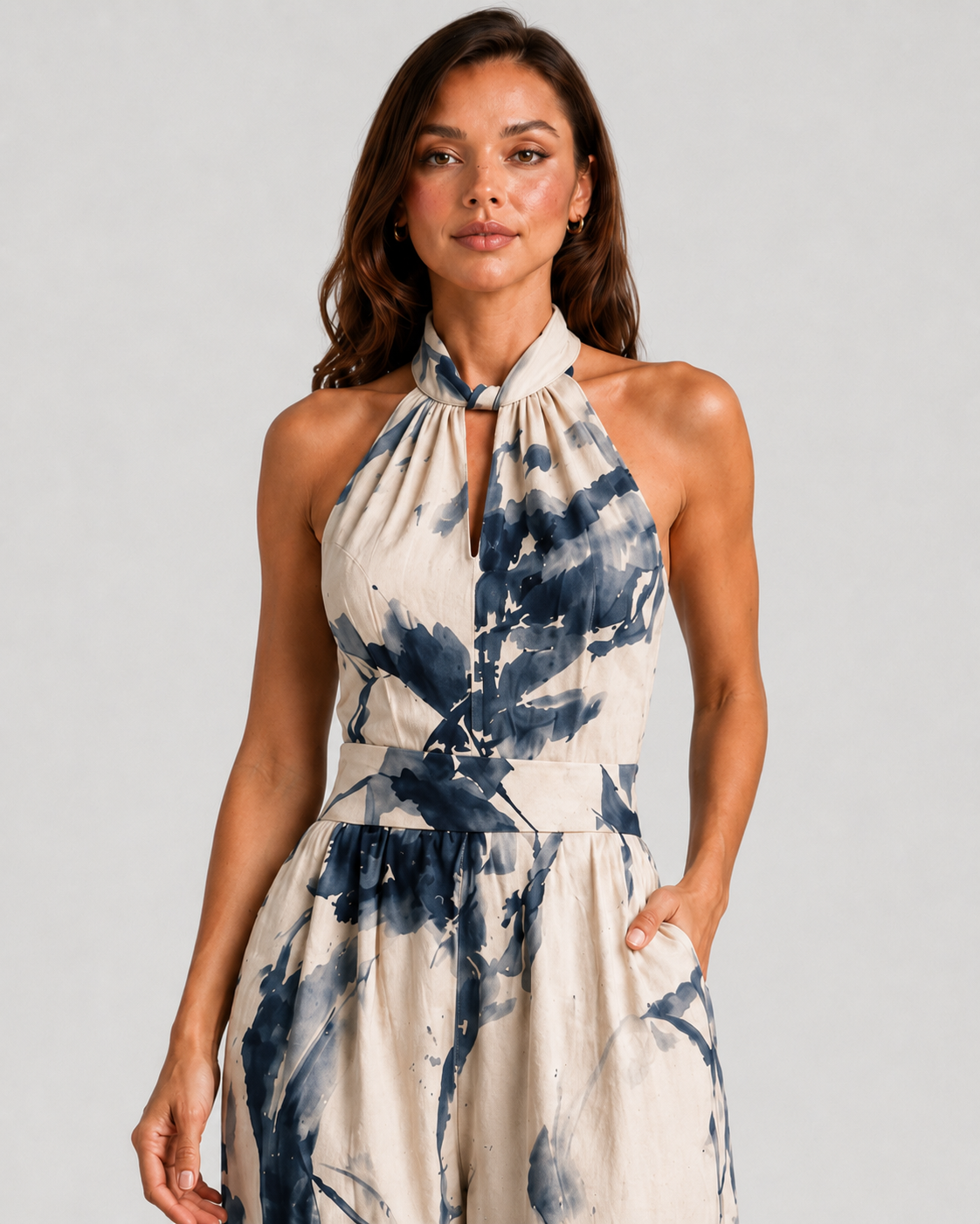 Woman wearing a printed halter neckline wide-leg jumpsuit with a relaxed fit, breathable fabric, side pockets and flowing resort-inspired silhouette.