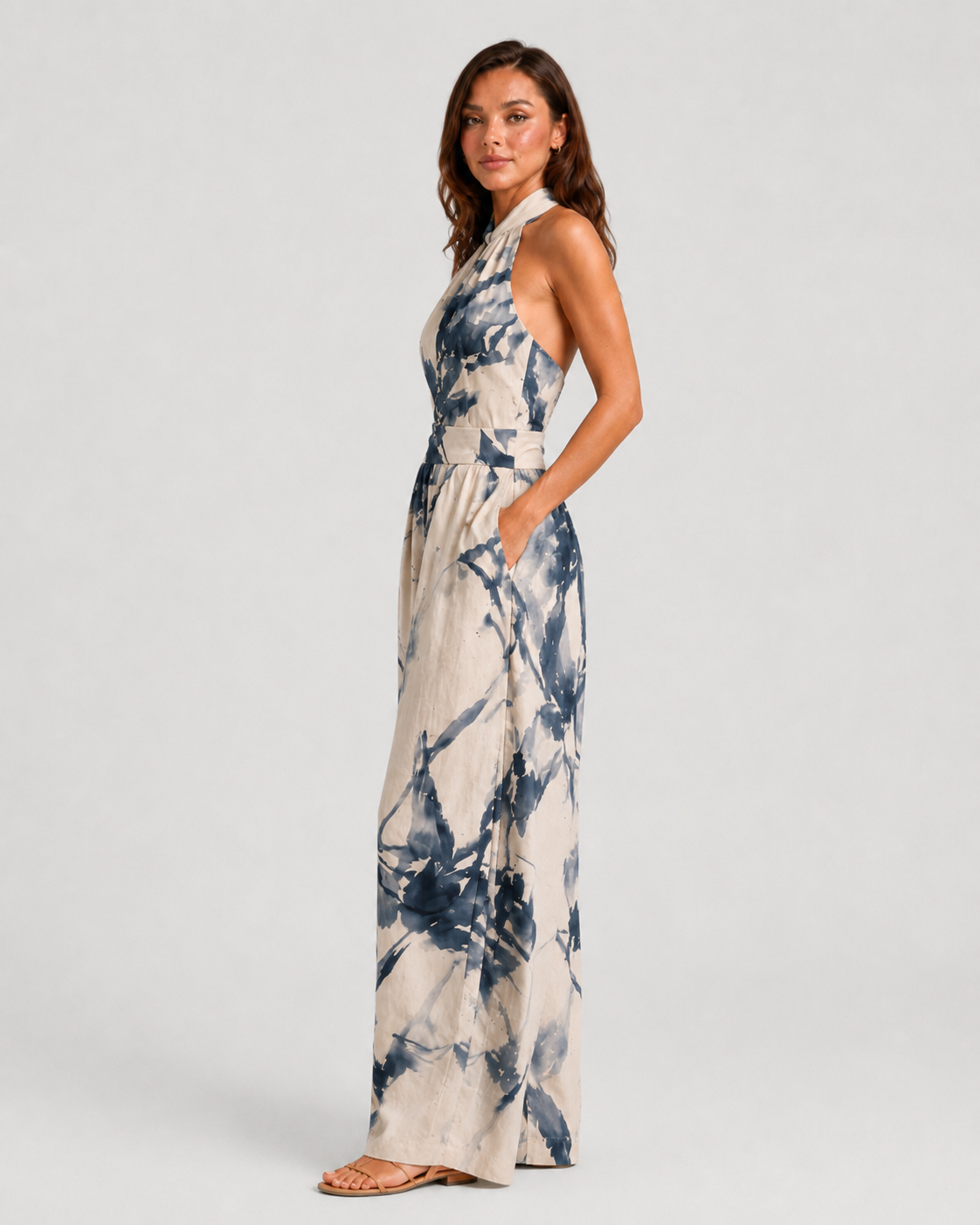 Woman wearing a printed halter neckline wide-leg jumpsuit with a relaxed fit, breathable fabric, side pockets and flowing resort-inspired silhouette.