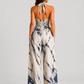 Woman wearing a printed halter neckline wide-leg jumpsuit with a relaxed fit, breathable fabric, side pockets and flowing resort-inspired silhouette.