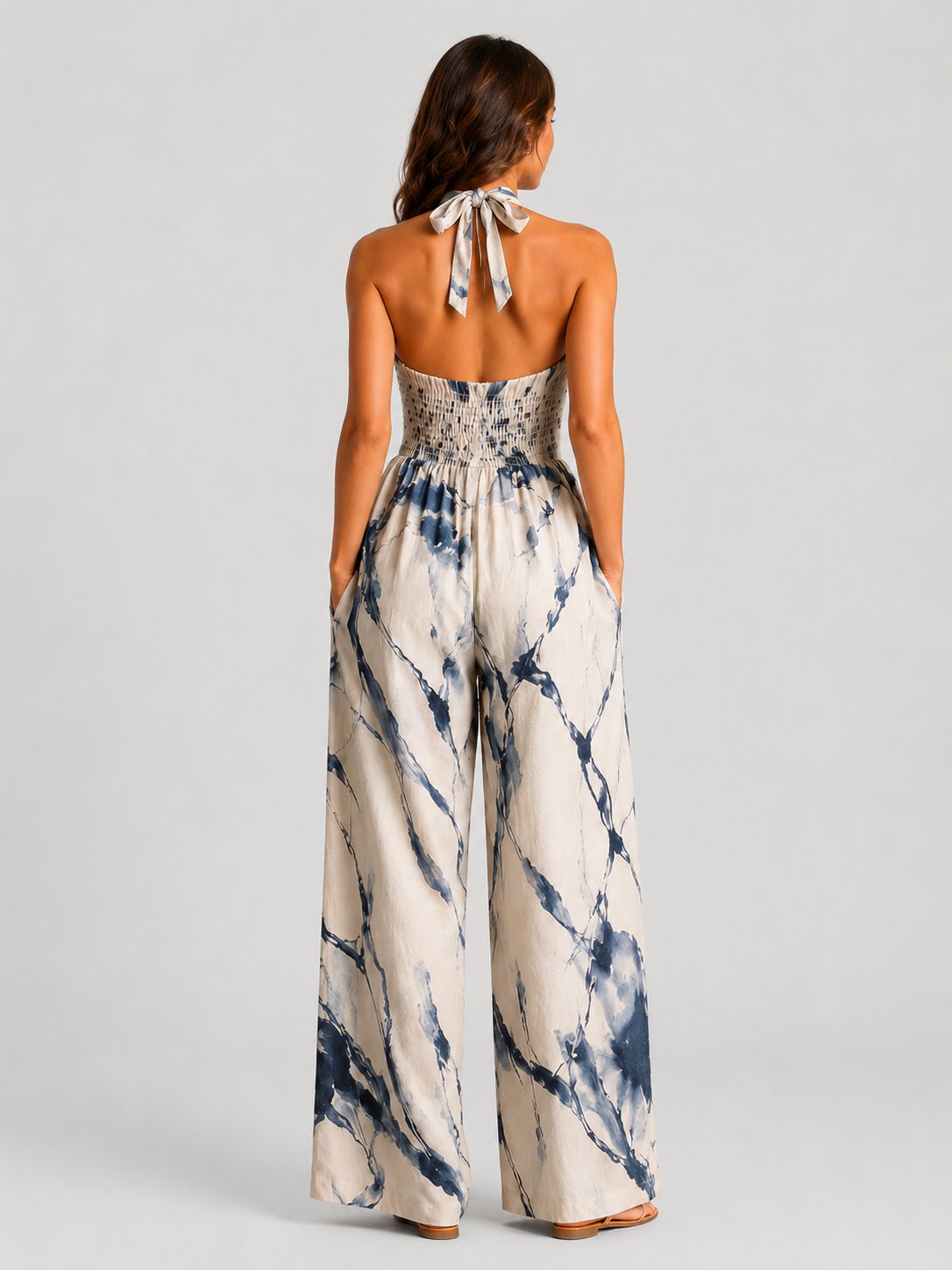 Woman wearing a printed halter neckline wide-leg jumpsuit with a relaxed fit, breathable fabric, side pockets and flowing resort-inspired silhouette.