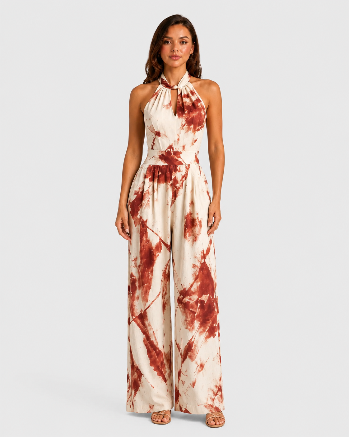 Woman wearing a printed halter neckline wide-leg jumpsuit with a relaxed fit, breathable fabric, side pockets and flowing resort-inspired silhouette.