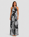 Woman wearing a printed halter neckline wide-leg jumpsuit with a relaxed fit, breathable fabric, side pockets and flowing resort-inspired silhouette.