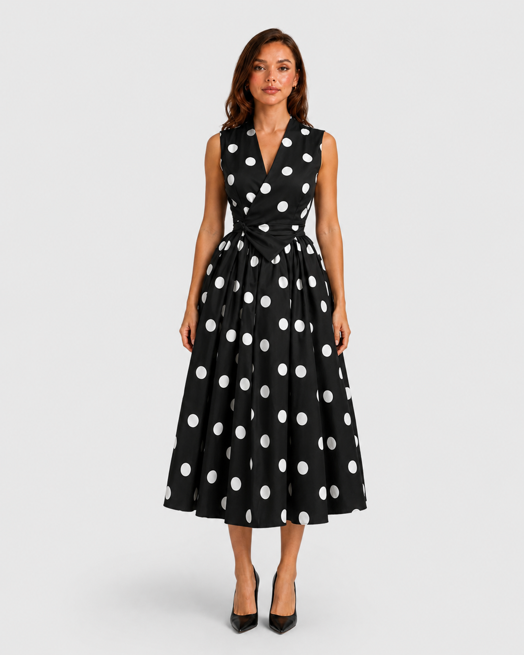 Women's black and white polka dot midi dress with sleeveless V-neckline, waist tie detail, and flowing full skirt in a vintage-inspired silhouette.