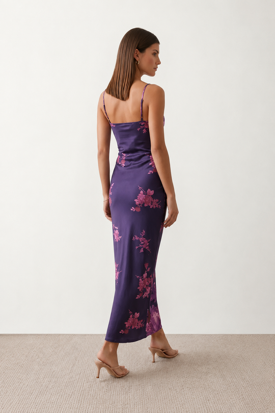 Woman wearing the Milota glossy floral slip maxi dress featuring a baroque-inspired floral print, deep V-neckline, adjustable spaghetti straps, low draped back, satin-look finish, and body-skimming floor-length silhouette, ideal for wedding guests and formal occasions.