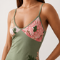 Woman wearing the Milota glossy floral slip maxi dress featuring a baroque-inspired floral print, deep V-neckline, adjustable spaghetti straps, low draped back, satin-look finish, and body-skimming floor-length silhouette, ideal for wedding guests and formal occasions.
