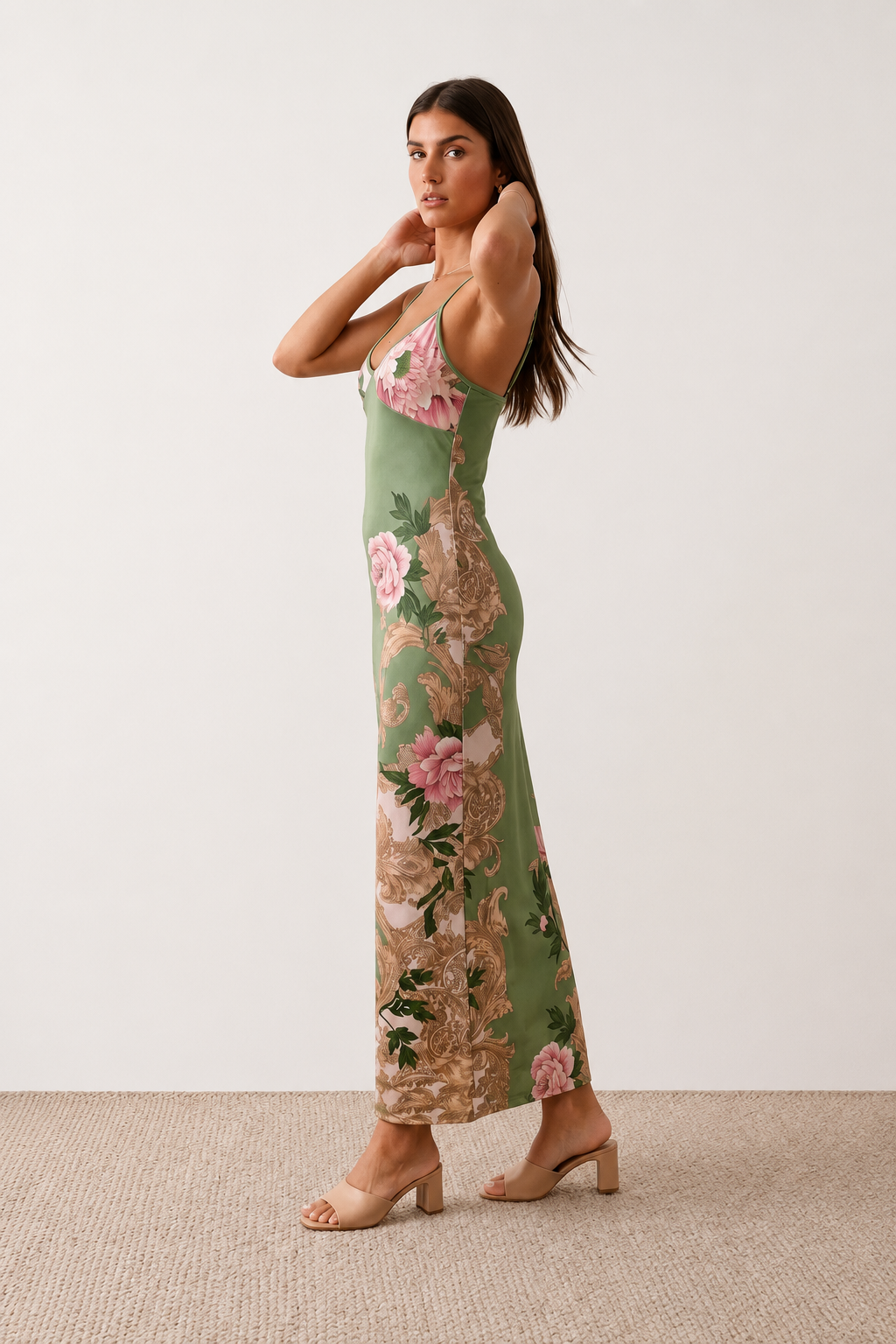 Woman wearing the Milota glossy floral slip maxi dress featuring a baroque-inspired floral print, deep V-neckline, adjustable spaghetti straps, low draped back, satin-look finish, and body-skimming floor-length silhouette, ideal for wedding guests and formal occasions.