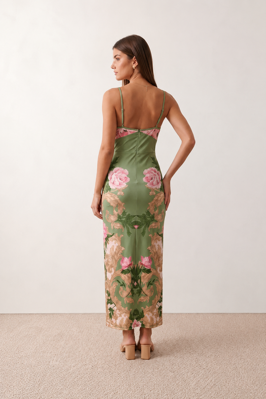 Woman wearing the Milota glossy floral slip maxi dress featuring a baroque-inspired floral print, deep V-neckline, adjustable spaghetti straps, low draped back, satin-look finish, and body-skimming floor-length silhouette, ideal for wedding guests and formal occasions.