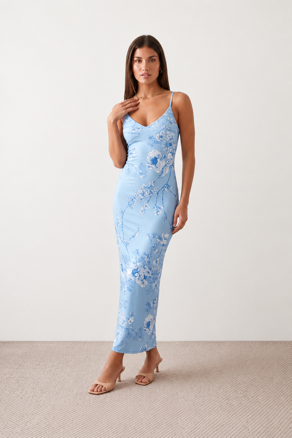 Woman wearing the Milota glossy floral slip maxi dress featuring a baroque-inspired floral print, deep V-neckline, adjustable spaghetti straps, low draped back, satin-look finish, and body-skimming floor-length silhouette, ideal for wedding guests and formal occasions.
