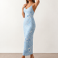 Woman wearing the Milota glossy floral slip maxi dress featuring a baroque-inspired floral print, deep V-neckline, adjustable spaghetti straps, low draped back, satin-look finish, and body-skimming floor-length silhouette, ideal for wedding guests and formal occasions.